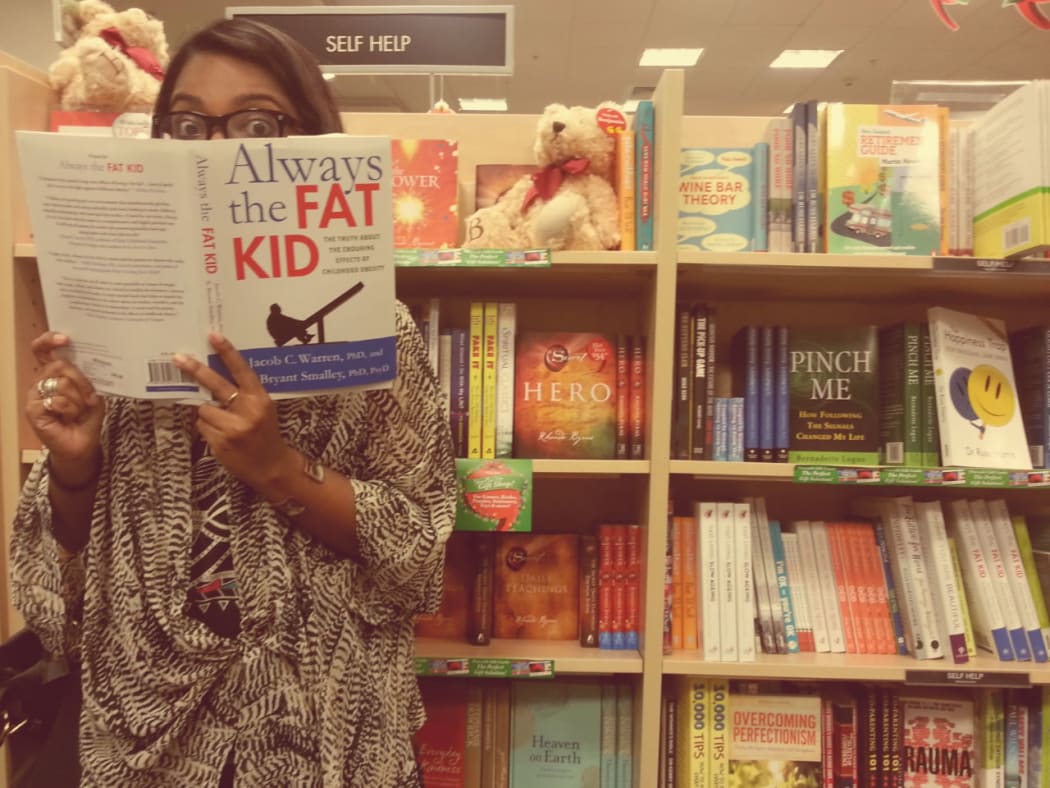 Saziah holding a book entitled "Always the Fat Kid".
