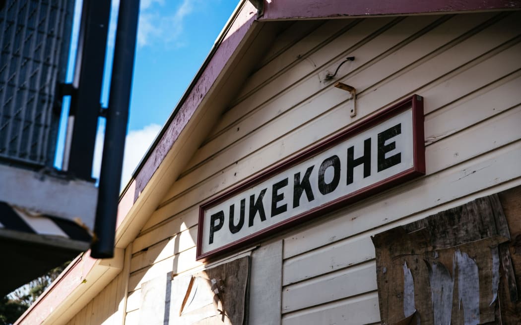 A sign that says Pukekohe on an old railway building.