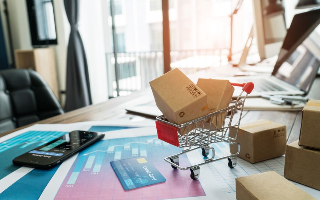 E-commerce. Paper boxes in shopping cart and credit card with smartphone on sales data economic growth graph, online shopping and payments, banking, buying and selling services online on network.