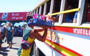 Street vendors at the Apia bus station can be seen winding in and out amongst the colorful Samoan buses selling food and drinks to passengers.