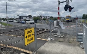 A train comes through a level crossing in Takanini