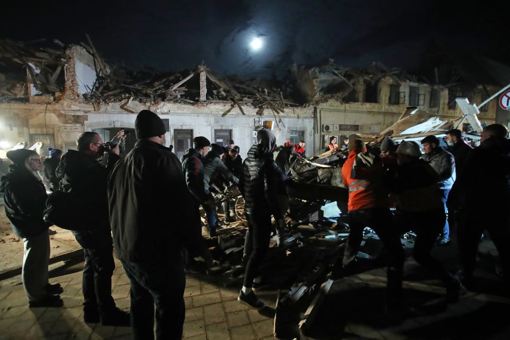 Volunteers and fans of the Croatian football club Dinamo clear rubble from damaged buildings in Petrinja.