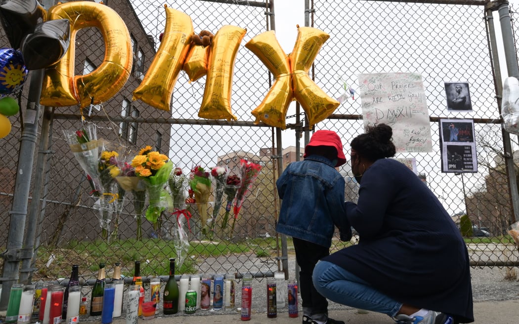 A woman and a young child light a candle at a makeshift memorial for hip-hop star DMX outside White Plains hospital in White Plains, New York on April 9, 2021.