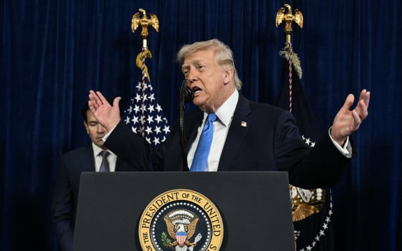 (L/R) US Secretary of State Marco Rubio looks on as US President Donald Trump speaks to the press following US military actions in Venezuela, at his Mar-a-Lago residence in Palm Beach, Florida, on January 3, 2026. President Trump said Saturday that US forces had captured Venezuelan leader Nicolas Maduro after launching a "large scale strike" on the South American country. (Photo by Jim WATSON / AFP)