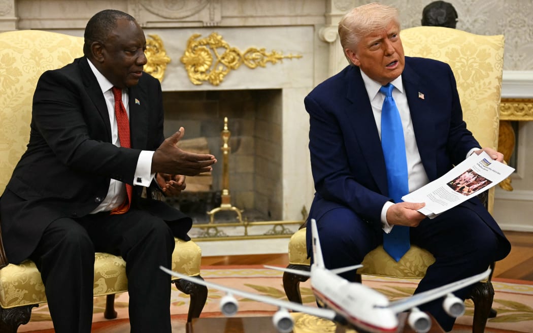 US President Donald Trump shows pictures as he meets with South African President Cyril Ramaphosa in the Oval Office of the White House in Washington, DC, on May 21, 2025. South African President Cyril Ramaphosa meets Donald Trump on Wednesday amid tensions over Washington's resettlement of white Afrikaners that the US president claims are the victims of "genocide." (Photo by Jim WATSON / AFP)
