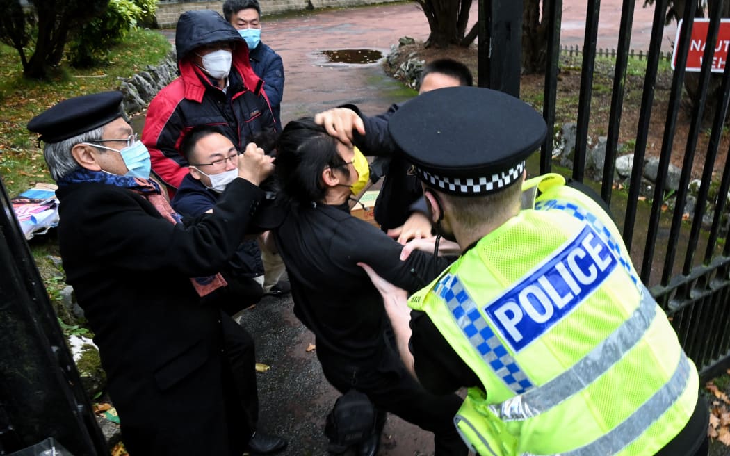 This handout from The Chaser News taken on 16 October, 2022 and released to AFP on 17 October shows an incident involving a scuffle between a Hong Kong pro-democracy protester, centre, and Chinese consulate staff, as a British police officer attempts to intervene, during a demonstration outside the consulate in Manchester.
