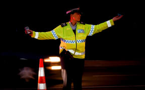 A police officer directing traffic at a alcohol check point.