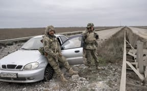 Ukrainian soldiers stand guard on the road from Mykolaiv to Kherson.