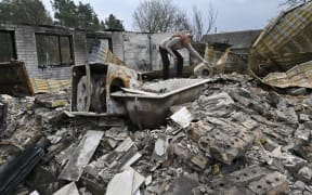A woman examines the debris of her destroyed house in the village of Rusaniv, in the Kyiv region on 16 April.