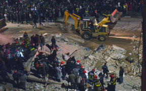 Emergency personnel search for victims in the rubble of two collapsed buildings in the Al Massira area of Fes late on 9 December, 2025.
