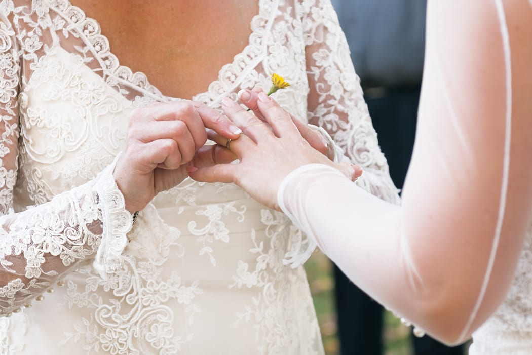 Same sex gay lesbian bride places ring on finger during wedding ceremony