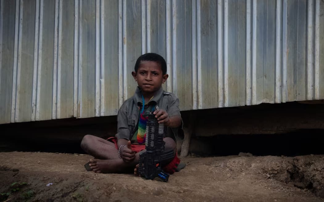 A young child holds a toy gun amid concerns about the flow of weapons in the country. (ABC News: Marian Faa)