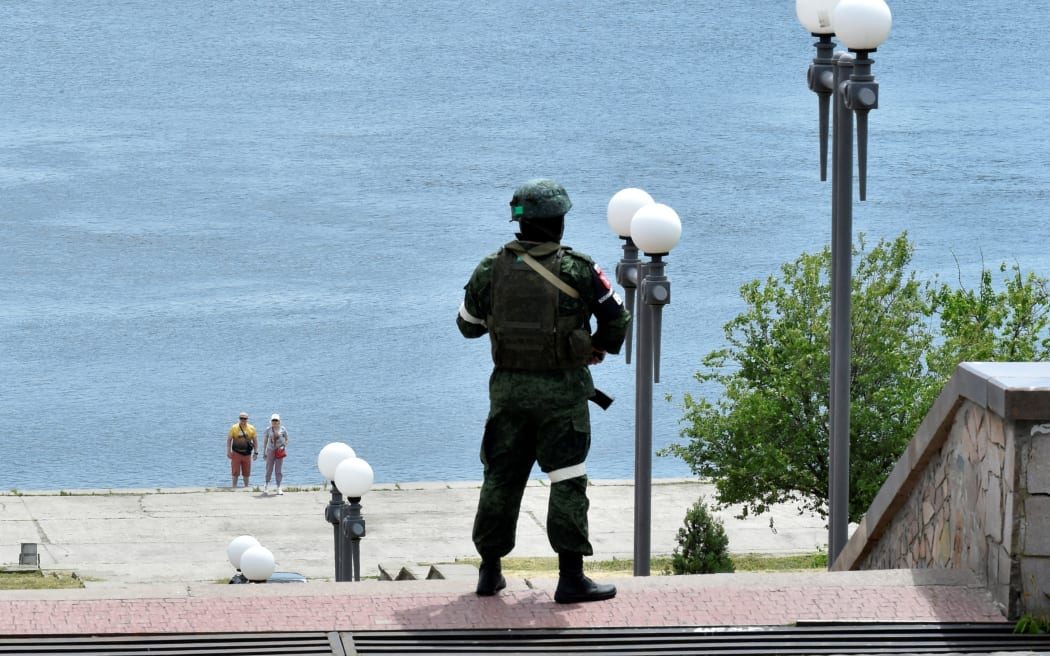In this file photo taken on May 20, 2022 a Russian serviceman patrols at a river bank in Kherson, amid the ongoing Russian military action in Ukraine.