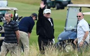 US President Donald Trump (C) gestures as he walks during a round of golf on the Ailsa course at Trump Turnberry, the luxury golf resort of US President Donald Trump, in Turnberry, southwest of Glasgow, Scotland, during the private part of his four-day UK visit.