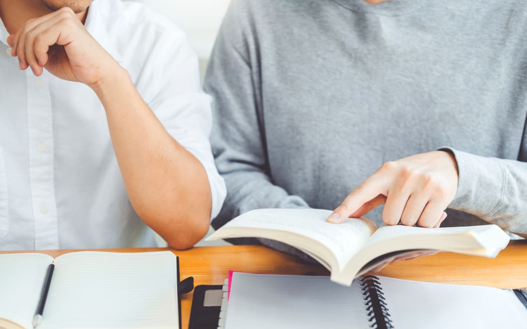 High school or college students studying and reading together in library