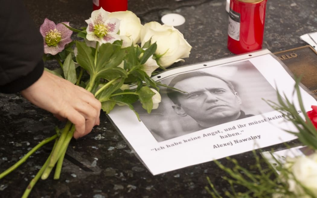 A protester is bringing flowers for Alexei Navalny while hundreds of people are taking part in a vigil to commemorate his death at Roncalli Square in Cologne, Germany, on February 18, 2024. (Photo by Ying Tang/NurPhoto) (Photo by Ying Tang / NurPhoto / NurPhoto via AFP)