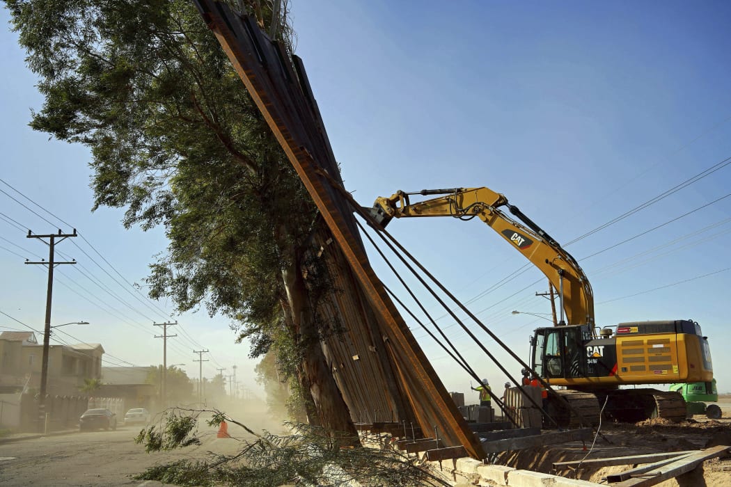 A construction crew works on a fallen section of the US-Mexico border wall as seen from Mexicali, Baja California state, Mexico, on January 29, 2020.