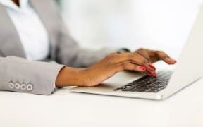 African businesswoman's hands working on laptop.