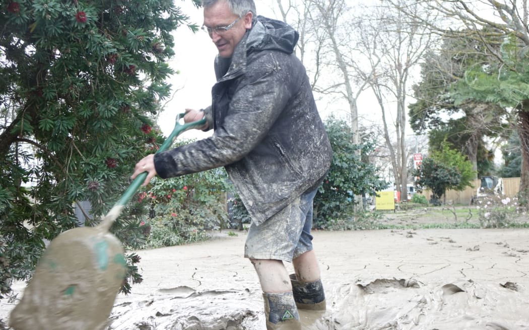 Mike Sullivan digging mud from the driveway of his Anzac Parade home.