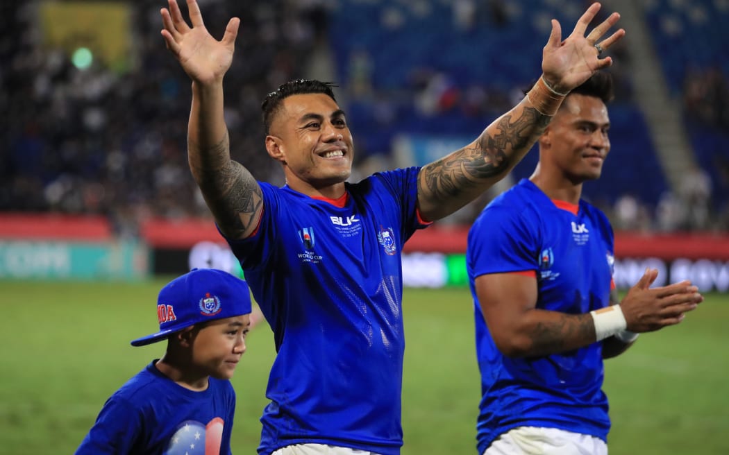 Tusi Pisi (c) waves to the crowd alongside his son Theron.
