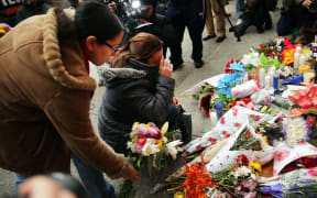 Women place flowers at a memorial to the two New York police officers shot and killed in the Bedford Stuyvesant neighborhood of Brooklyn.
