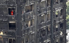 Members of the emergency services work on the middle floors of the charred remnains of the Grenfell Tower block in Kensington, west London, on June 17, 2017, follwing the June 14 fire at the residential building.