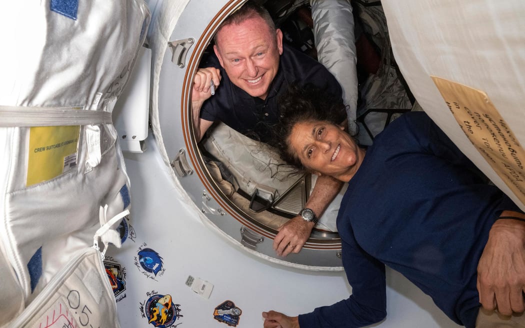 In this photo from NASA, astronauts Butch Wilmore and Suni Williams appear inside the vestibule between the forward port on the International Space Station's Harmony module and Boeing's Starliner spacecraft in June.