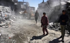 Palestinians clear a road from building rubble with a bulldozer following overnight Israeli bombardment which hit the al-Habash family home at the Nuseirat refugee camp in the central Gaza Strip on March 20, 2024, amid ongoing battles between Israel and the militant group Hamas. (Photo by AFP)