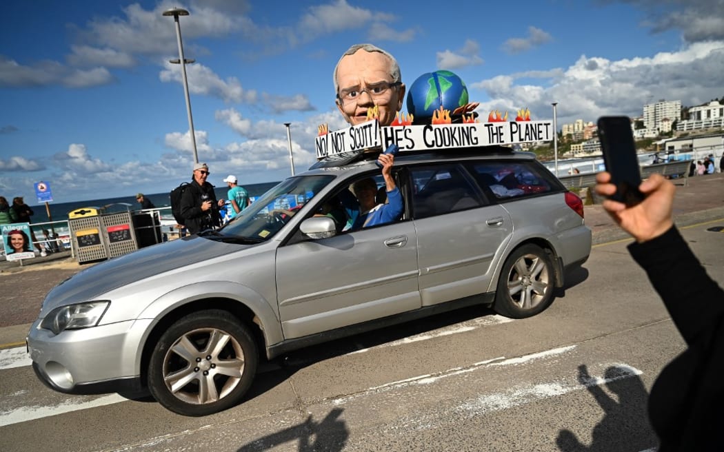 A vehicle with a giant head of Australian Prime Minister Scott Morrison is seen as people arrive to vote during Australia's general election at a polling station at Bondi Beach in Sydney on May 21, 2022. (Photo by STEVEN SAPHORE / AFP)