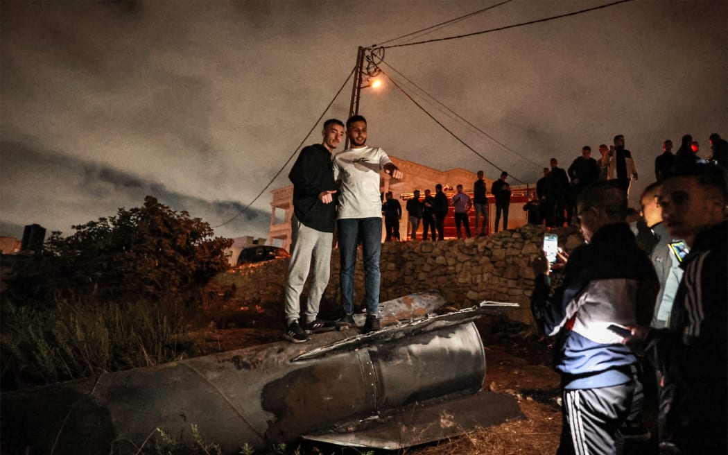 Palestinian youths pose for a picture atop a fallen projectile after Iran launched a barrage of missiles at Israel in response to the killings of Lebanese Hezbollah leader Nasrallah and other Iran-backed militants, in Ramallah in the occupied West Bank on October 1, 2024. Reports said Iran fired between 150 and 200 missiles in the attack, the country's second on Israel after a missile and drone attack in April in response to a deadly Israeli air strike on the Iranian consulate in Damascus. (Photo by Zain JAAFAR / AFP)