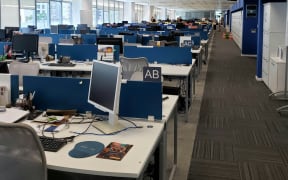 An open office plan with computers and items on desks in rows.