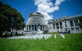 Signs from protestors sit outside Parliament during the apology for abuse in state care