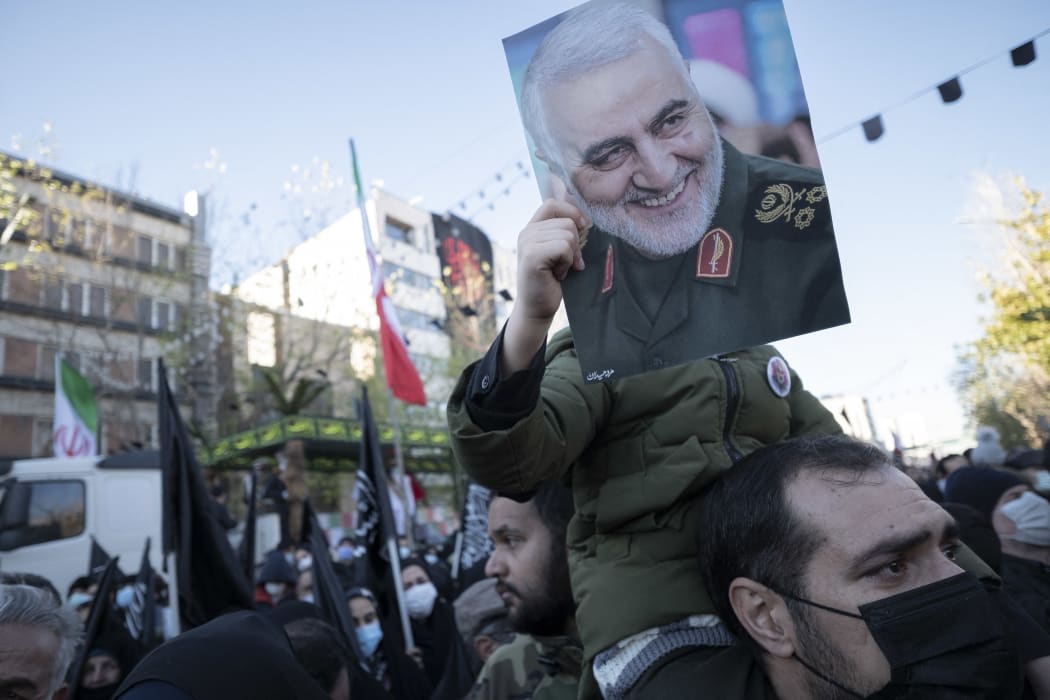 An Iranian boy holds a portrait of former commander of the Islamic Revolutionary Guard Corps General Qasem Soleimani during a funeral for unknown martyrs of the Iran-Iraq war (1980-88) in downtown Tehran, on Thursday.
