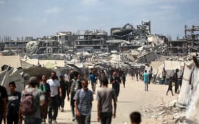 Palestinians walk along a street near war-damaged buildings in Gaza City on August 8, 2025. Israel's military will "take control" of Gaza City under a plan proposed by Prime Minister Benjamin Netanyahu and approved by his security cabinet, triggered a wave of criticism from across the world. (Photo by Bashar TALEB / AFP)