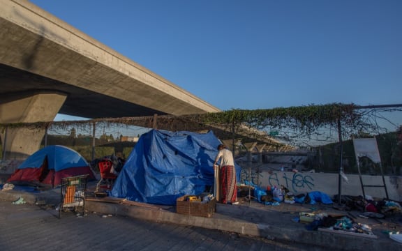 Nicole (last name not given) 40 years-old, fixes her tent over the bridge of the 110 Freeway, Los Angeles.
