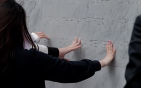 Members of the public, including the family and friends of victims, gathered to place their hands on the memorial.