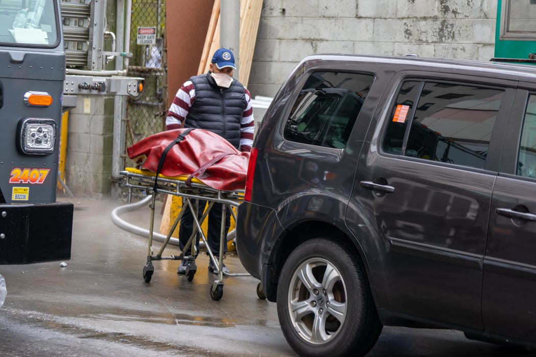 A funeral home employee loads a body to be transported a refrigerated trailer in New York City.