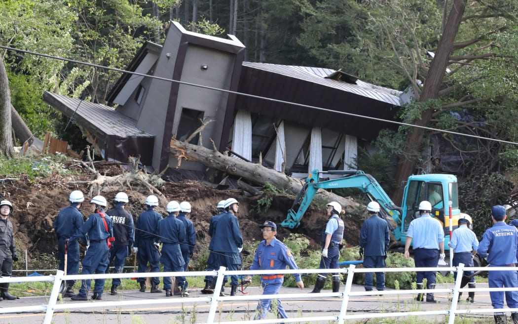 Police officers and fire crews at at a collapsed house in Atsuma, Hokkaido