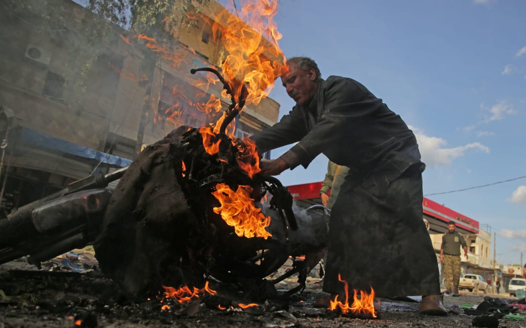 A Syrian man stands next to a burning motorcycle at the site of a car bomb explosion in the northern Syrian Kurdish town of Tal Abyad, on the border with Turkey, on November 2, 2019.