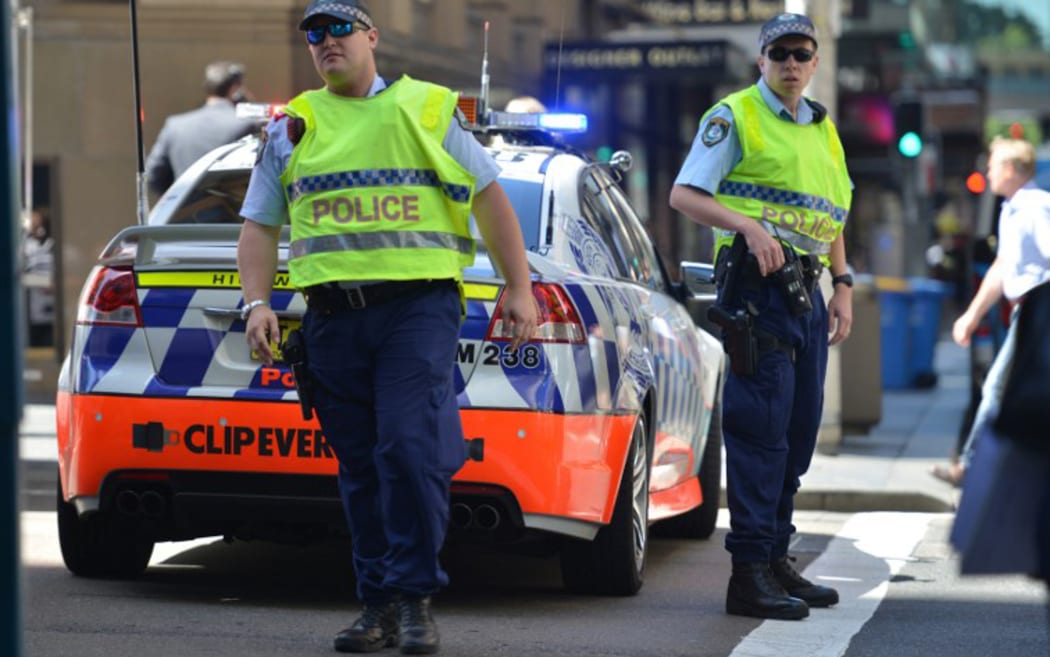 Police close a street where a cafe is being used to hold hostages in the central business district of Sydney