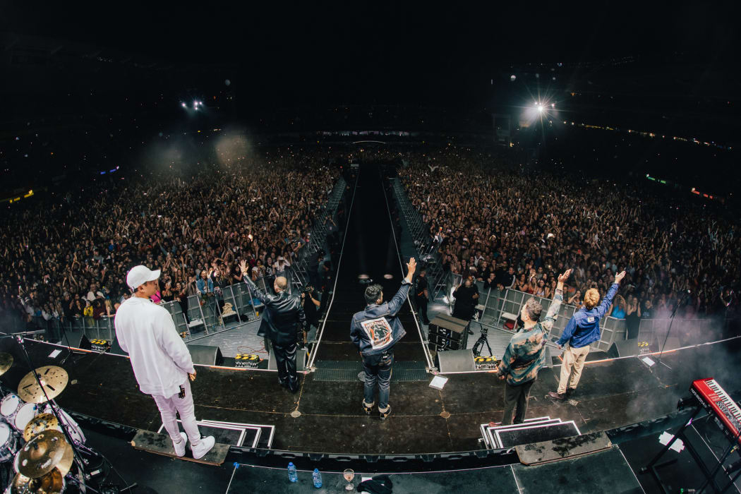Six60 waving to fans from the stage at Eden Park.
