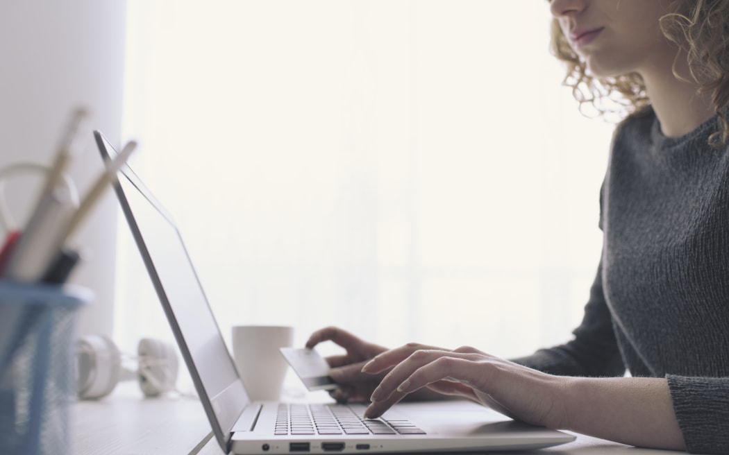 Woman doing online shopping using her laptop and a credit card, hands close up, e-commerce and online banking concept