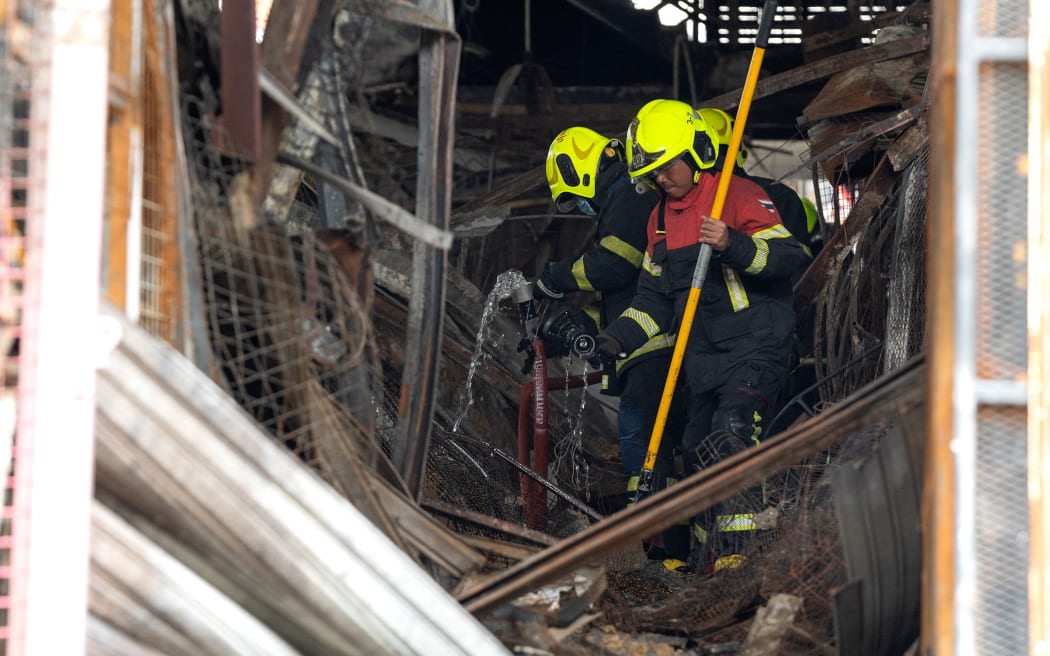 Firefighters walk through the wreckage and debris after a fire at a pet market next to Chatuchak market in Bangkok on June 11, 2024. A fire ripped through pet shops next to Bangkok's famed Chatuchak market early June 11, killing caged dogs, cats, birds and snakes, and damaging more than 100 stalls, police said.