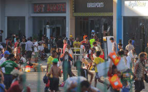 People carry items as crowds leave shops with looted goods amid a state of unrest in Port Moresby on January 10, 2024. Papua New Guinea's prime minister declared a 14-day state of emergency in the capital on January 11, 2024, after 15 people were killed in riots as crowds looted and burned shops. (Photo by STRINGER / AFP)