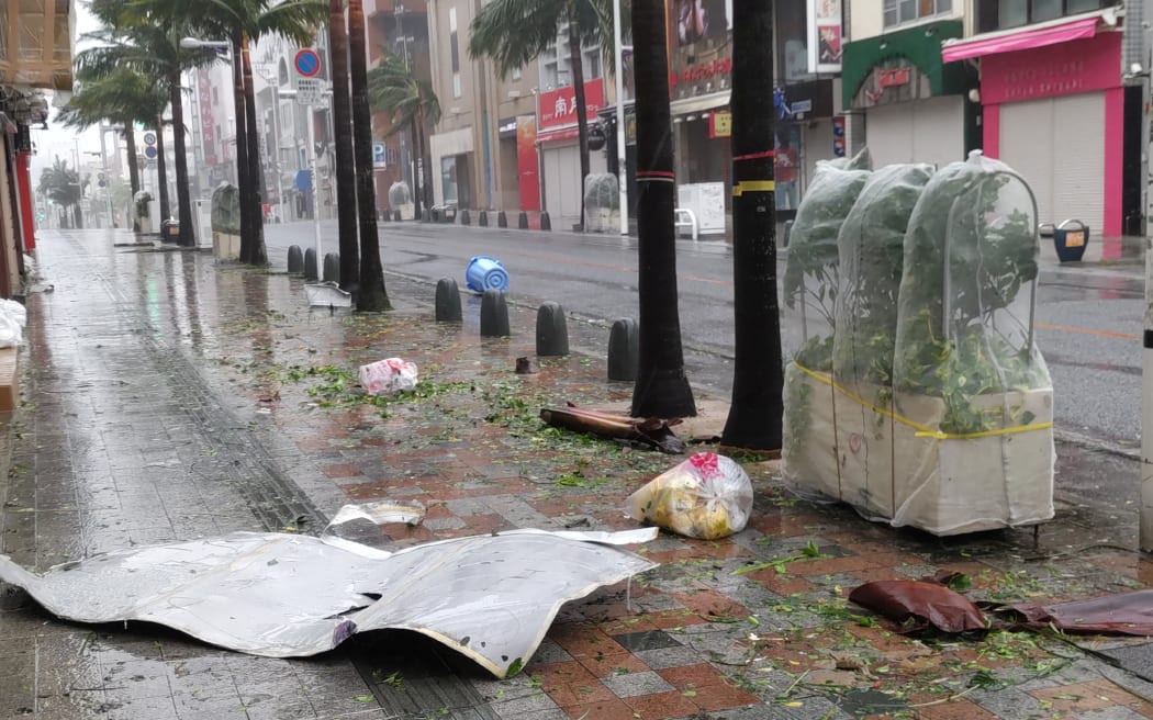 Scattered debris litters a downtown street as high winds brought by Typhoon Khanun hit the city of Naha, Okinawa prefecture on August 2, 2023. Hundreds of thousands of residents in southern Japan were left without power on August 2 as the powerful typhoon approached the island, bringing strong wind and heavy rain. (Photo by JIJI Press / AFP) / Japan OUT