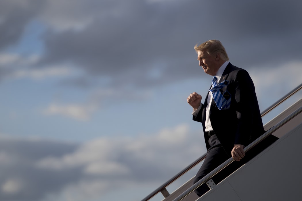 US President Donald Trump gives one of his habitual fist-pumping gestures to a gathered crowd as he exits Air Force One.