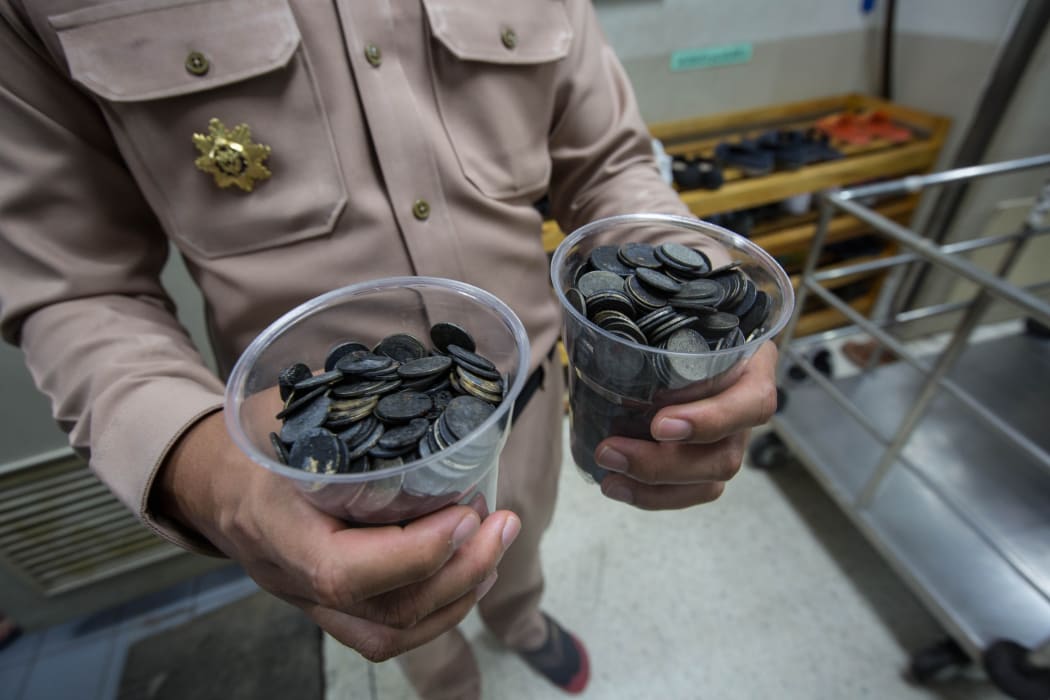 An officer shows the coins that the sea turtle ate over the years