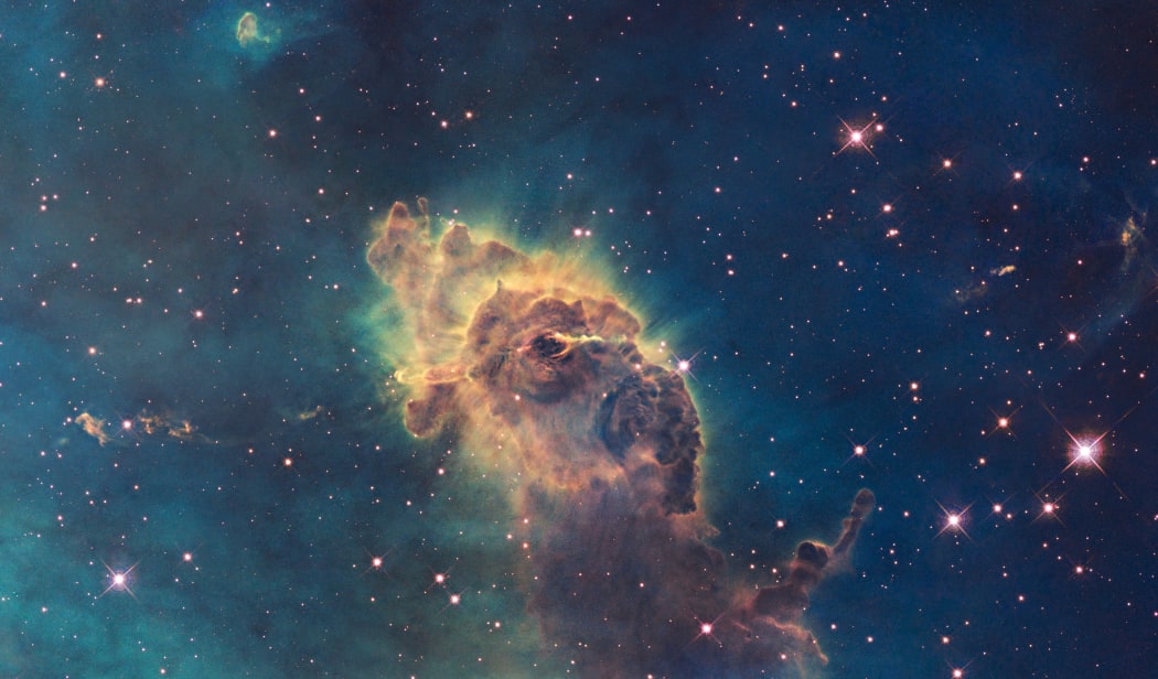 A photograph taken by the Hubble Space Telescope shows a three-light-year-long pillar of gas and dust in a nebula 7500 light years from Earth.