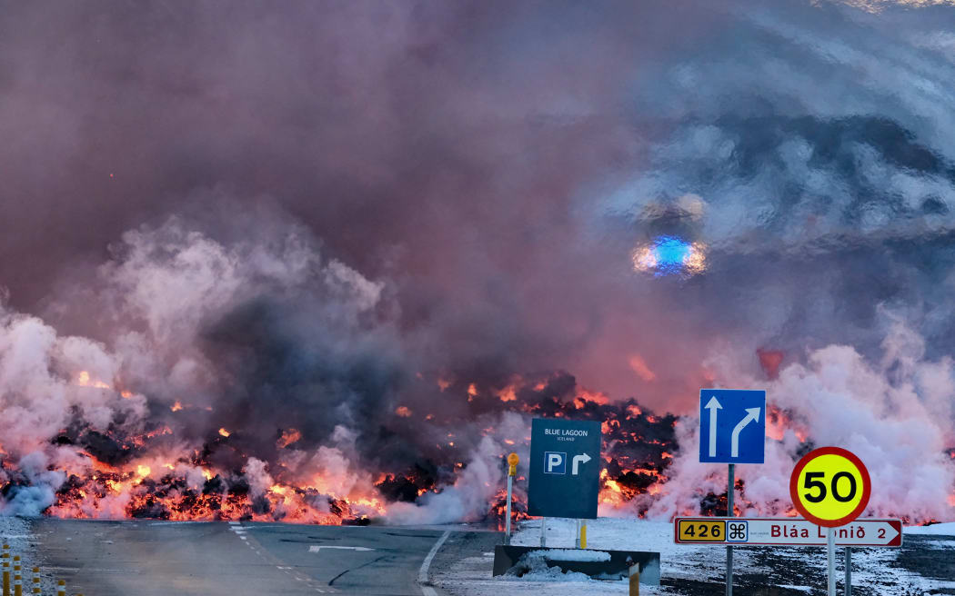 Molten lava is seen overflowing the road leading to the famous tourist destination "Blue Lagoon" near Grindavik, western Iceland on February 8, 2023. A volcanic eruption started on the Reykjanes peninsula in southwestern Iceland on Thursday, the third to hit the area since December, authorities said. (Photo by Kristinn Magnusson / AFP)