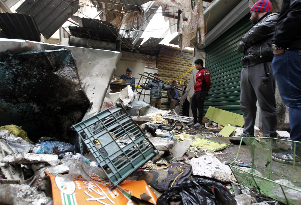 Iraqis look at the aftermath following a double blast in a busy market area in Baghdad's central al-Sinek neighbourhood on 31 December , 2016.